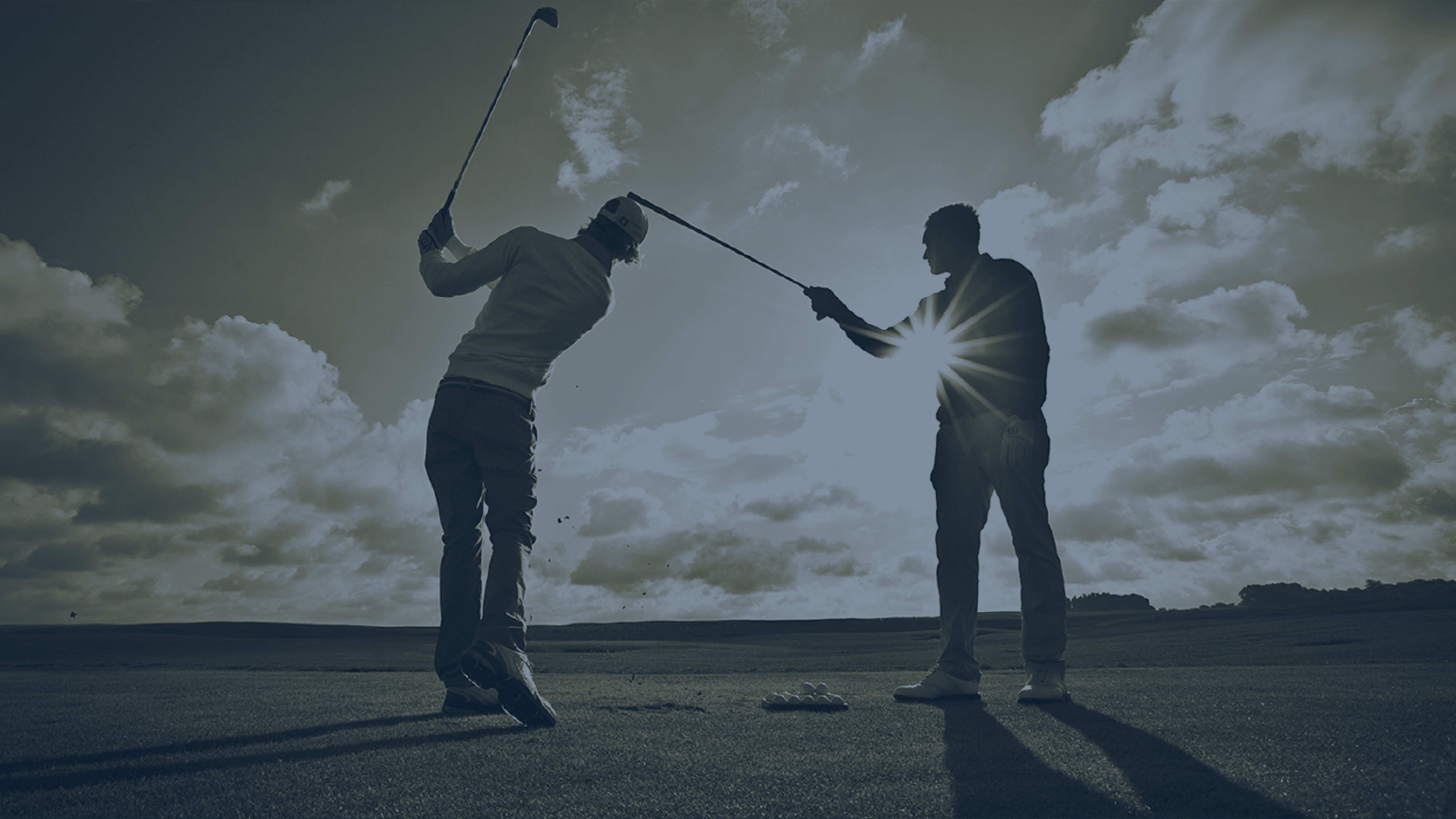 Silhouette of a golf coach guiding a player's swing at sunset with dramatic sky